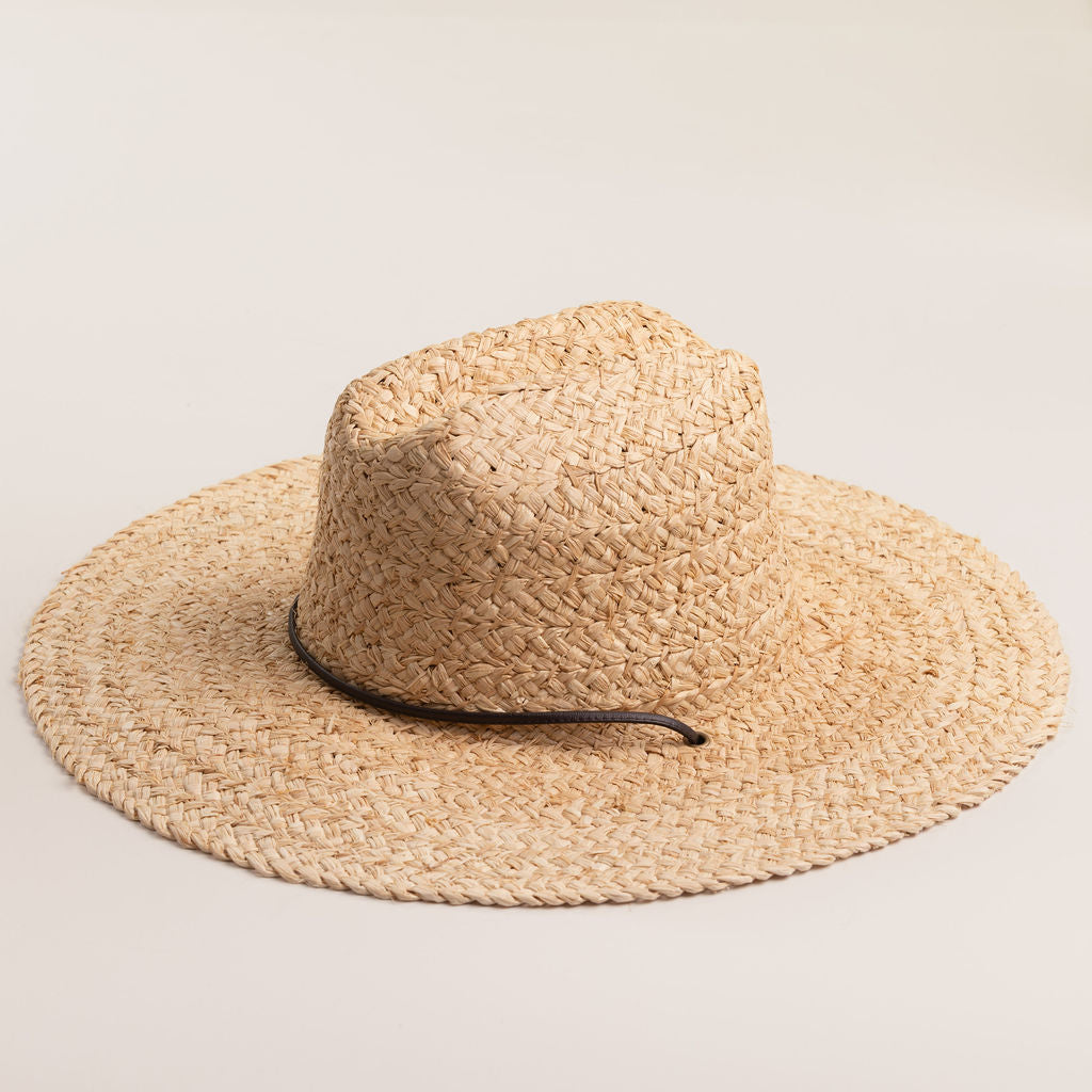 Natural colored straw hat with a wide brim on a light beige background