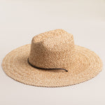 Natural colored straw hat with a wide brim on a light beige background