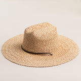 Natural colored straw hat with a wide brim on a light beige background