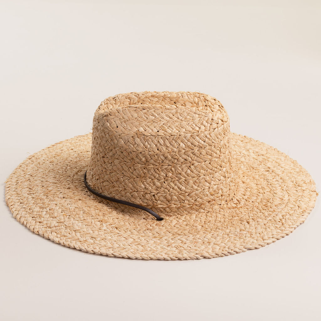 Natural colored straw hat with a wide brim on a light beige background