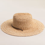 Natural colored straw hat with a wide brim on a light beige background