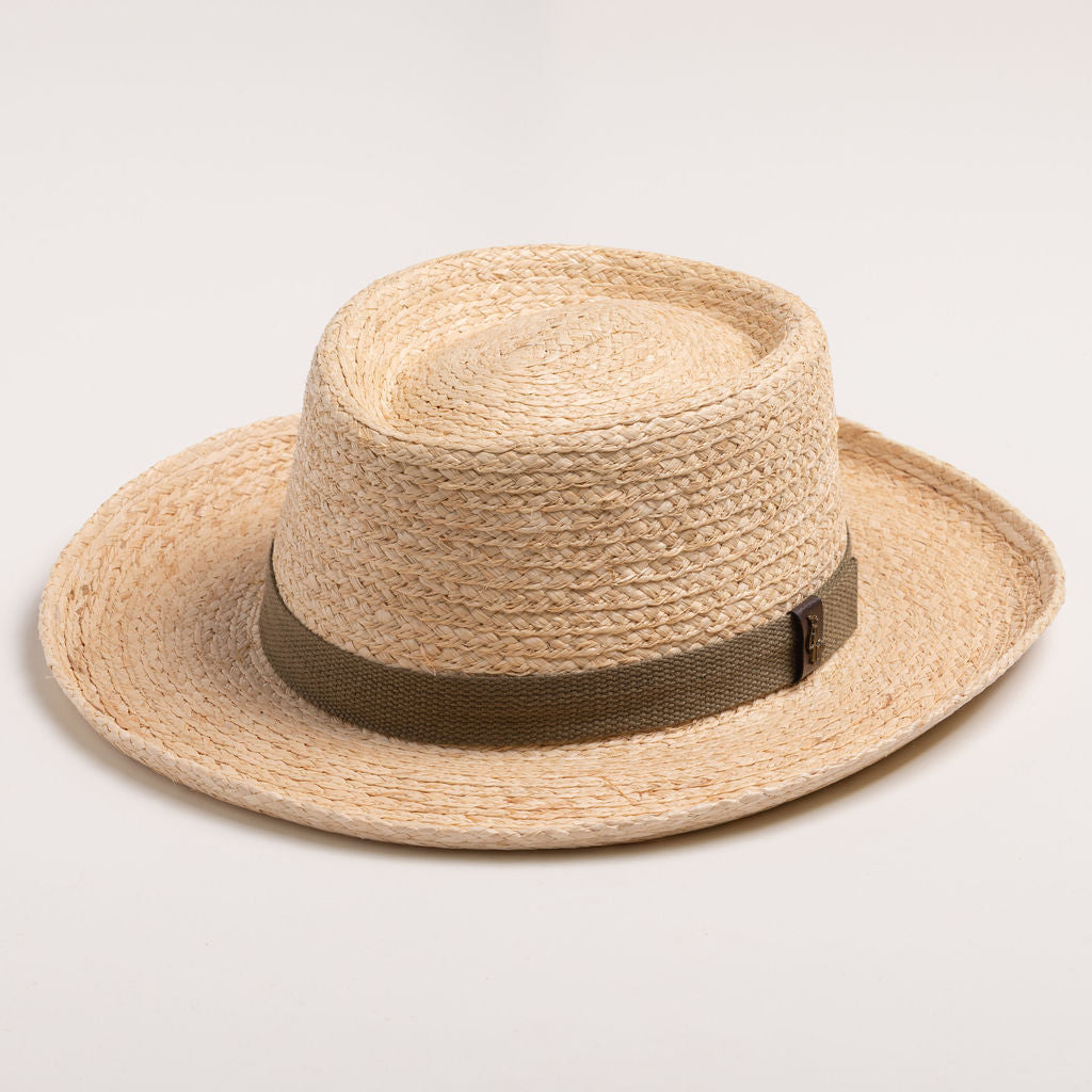 Natural colored straw hat with a brown band on a light beige background