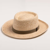 Natural colored straw hat with a brown band on a light beige background