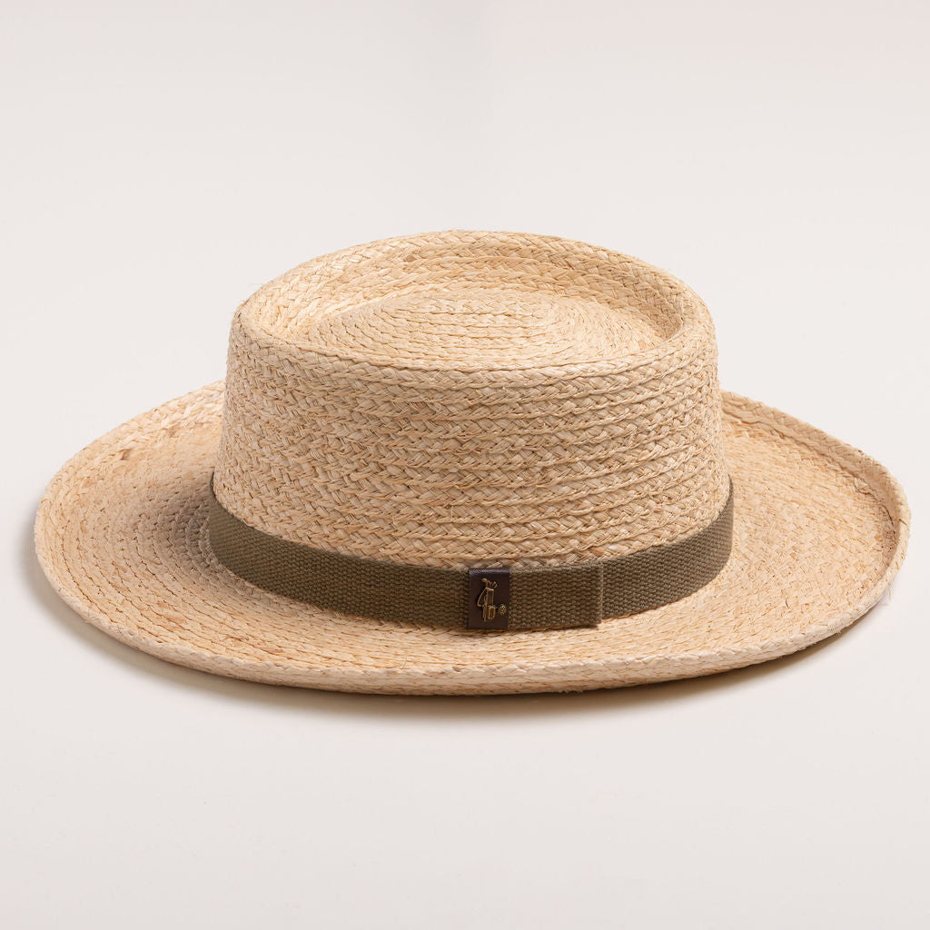 Natural colored straw hat with a brown band on a light beige background