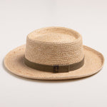 Natural colored straw hat with a brown band on a light beige background