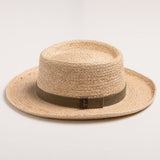 Natural colored straw hat with a brown band on a light beige background