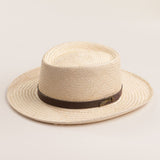 Natural colored straw hat with a brown band on a light beige background