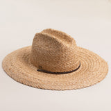 Natural colored straw hat with a wide brim on a light beige background