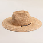 Natural colored straw hat with a wide brim on a light beige background