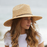 Woman wearing a natural colored straw hat with a blurred background