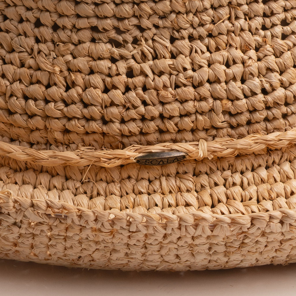 Close-up of a natural colored straw hat with the Scala logo pin