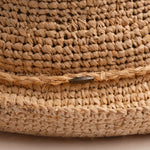 Close-up of a natural colored straw hat with the Scala logo pin