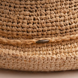 Close-up of a natural colored straw hat with the Scala logo pin