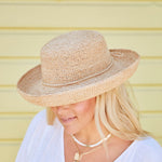 Woman wearing a natural colored straw hat facing downwards against a yellow striped background
