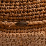 Close-up of a tea colored straw hat with the Scala logo pin