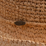 Close-up of a natural colored straw hat with a Scala logo pin