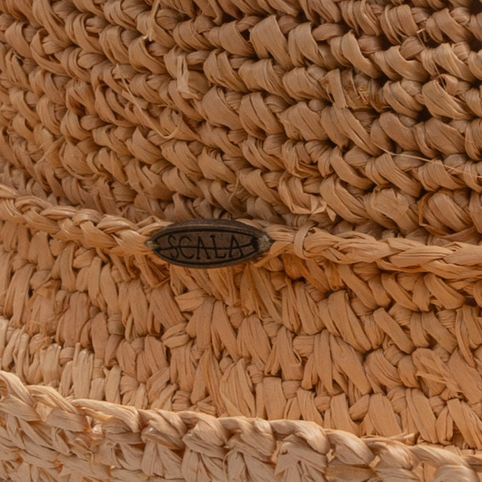 Close-up of a natural colored straw hat with a Scala logo pin