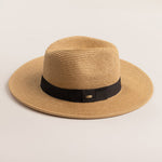 Toast colored straw hat with a black band on a light beige background