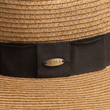 Close-up of a toast colored straw hat with a black band and Scala logo pin