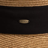 Close-up of a tea colored straw hat with a thick black band and Scala logo pin