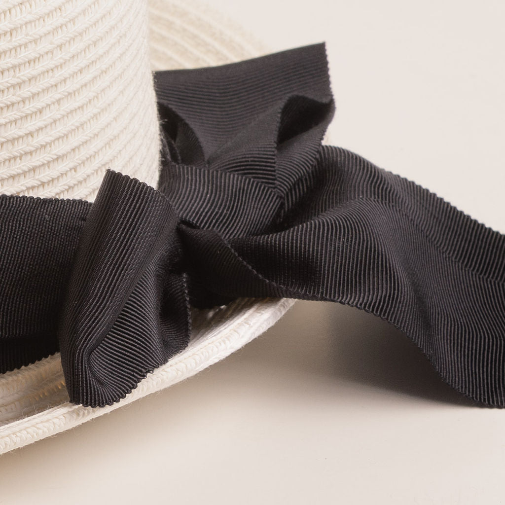 Close-up of a black ribbon bow on a white straw hat