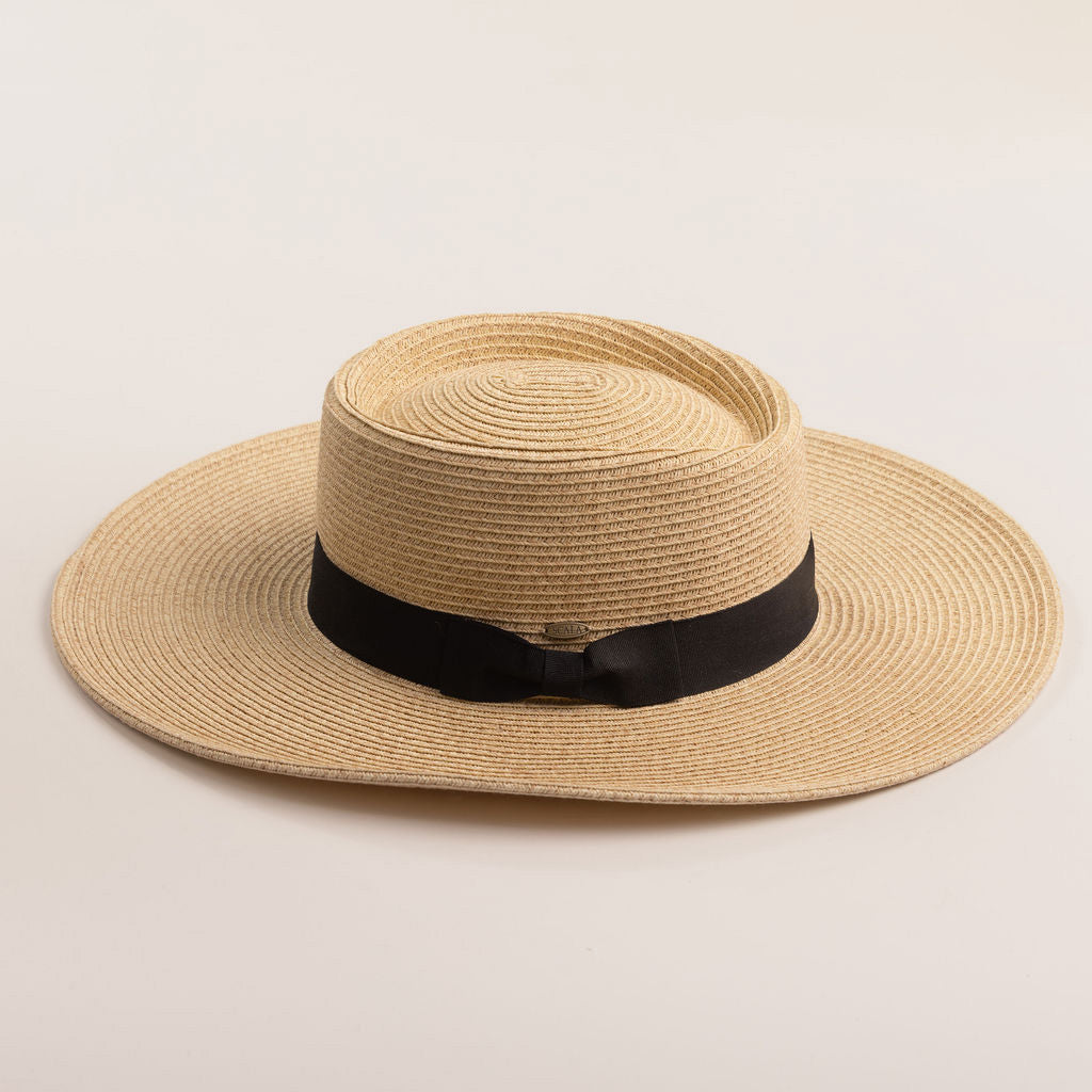 Natural colored straw hat with a black band on a beige background