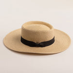 Natural colored straw hat with a black band on a beige background