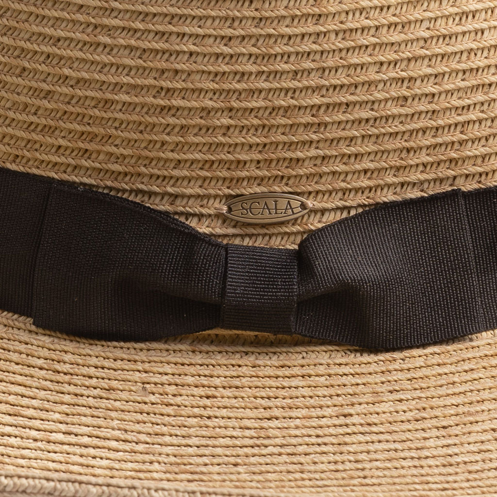 Close-up of a natural colored straw hat with black ribbon and Scala pin logo