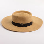 A natural straw sun hat with a black ribbon band and bow, photographed on a clean light gray background