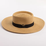 A natural straw sun hat with a black ribbon band and bow, photographed on a clean light gray background