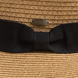 Close-up of a woven straw hat with a wide black ribbon bow and a small oval Scala brand pin at the center