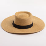 A natural straw sun hat with a black ribbon band and bow, photographed on a clean light gray background
