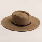 Brown straw hat with a wide brim on a light beige background