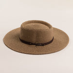 Brown straw hat with a wide brim on a light beige background