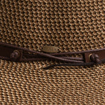 Close-up of a brown colored straw hat with the Scala logo pin and brown drawstring going into a golden colored eyelet