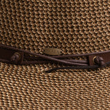 Close-up of a brown colored straw hat with the Scala logo pin and brown drawstring going into a golden colored eyelet