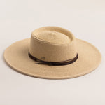 Natural colored straw hat with a wide brim on a light beige background