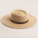Natural colored straw hat with a wide brim on a light beige background