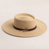 Natural colored straw hat with a brown band on a light beige background