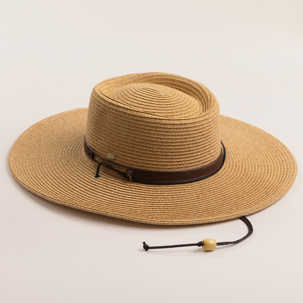 Toast colored straw hat with a brown band on a light beige background