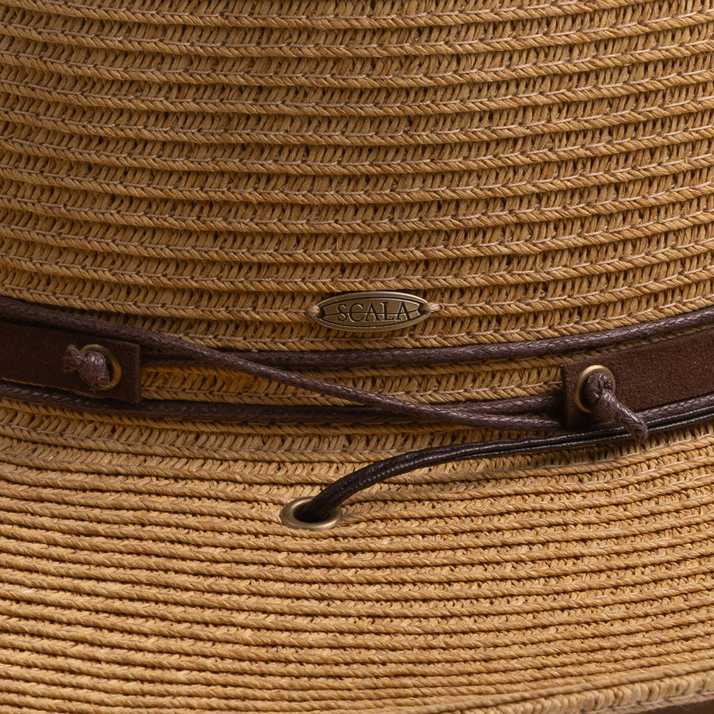 Close-up of a toast colored straw hat with the Scala logo pin and brown drawstring going into a golden colored eyelet