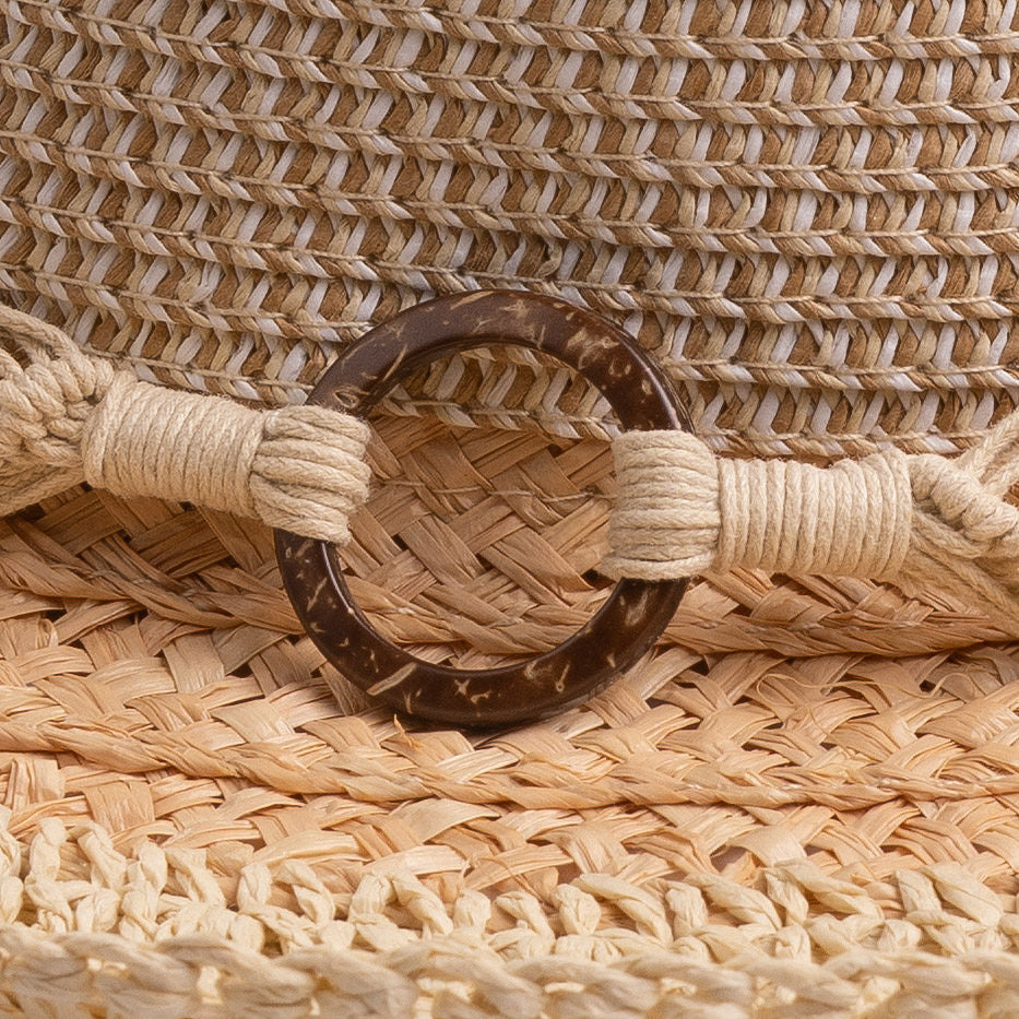 Close-up of a straw hat with a brown thick wooden buckle