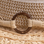 Close-up of a straw hat with a brown thick wooden buckle