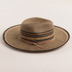 Multi-colored straw hat in shades of brown and black with a wide brim on a light beige background
