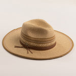 Natural colored straw hat in shades of brown with a wide brim on a light beige background