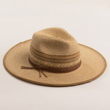 Natural colored straw hat in shades of brown with a wide brim on a light beige background