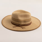 Natural colored straw hat in shades of brown with a wide brim on a light beige background