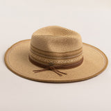 Natural colored straw hat in shades of brown with a wide brim on a light beige background