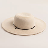 Ivory colored straw hat with a black band on a light beige background