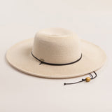 Ivory colored straw hat with a black band on a light beige background